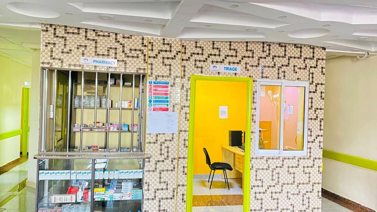 A corridor at Namo Hospital running between inpatient rooms toward a window at the far end.