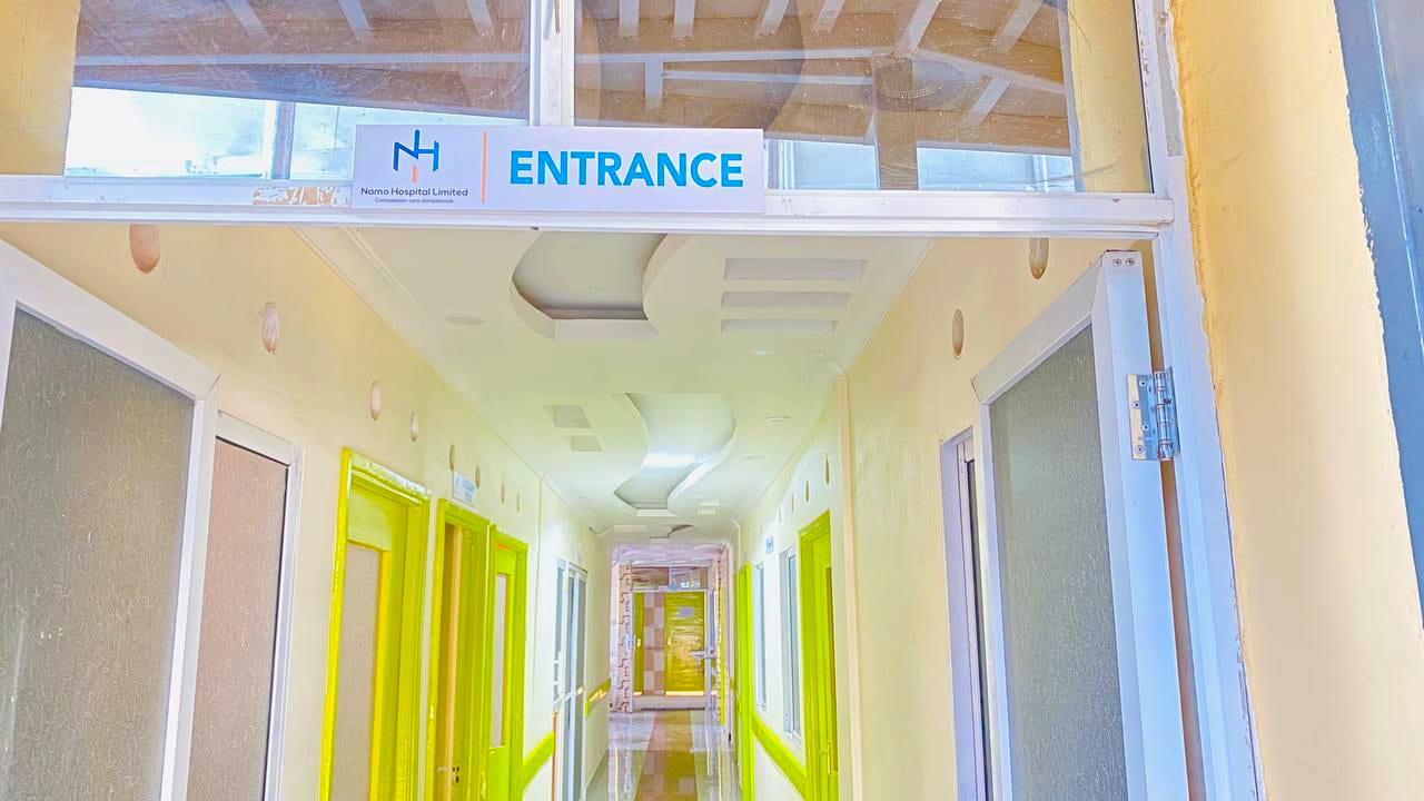 The entrance corridor inside Namo Hospital, with the Namo Hospital Limited sign above the doorway and consulting rooms along the passage.