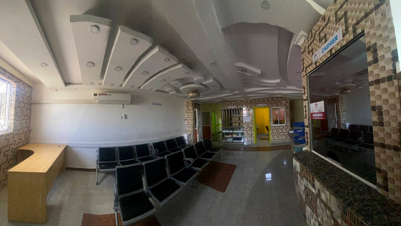 The reception area at Namo Hospital, with rows of seating, a cashier window and the triage room beyond.
