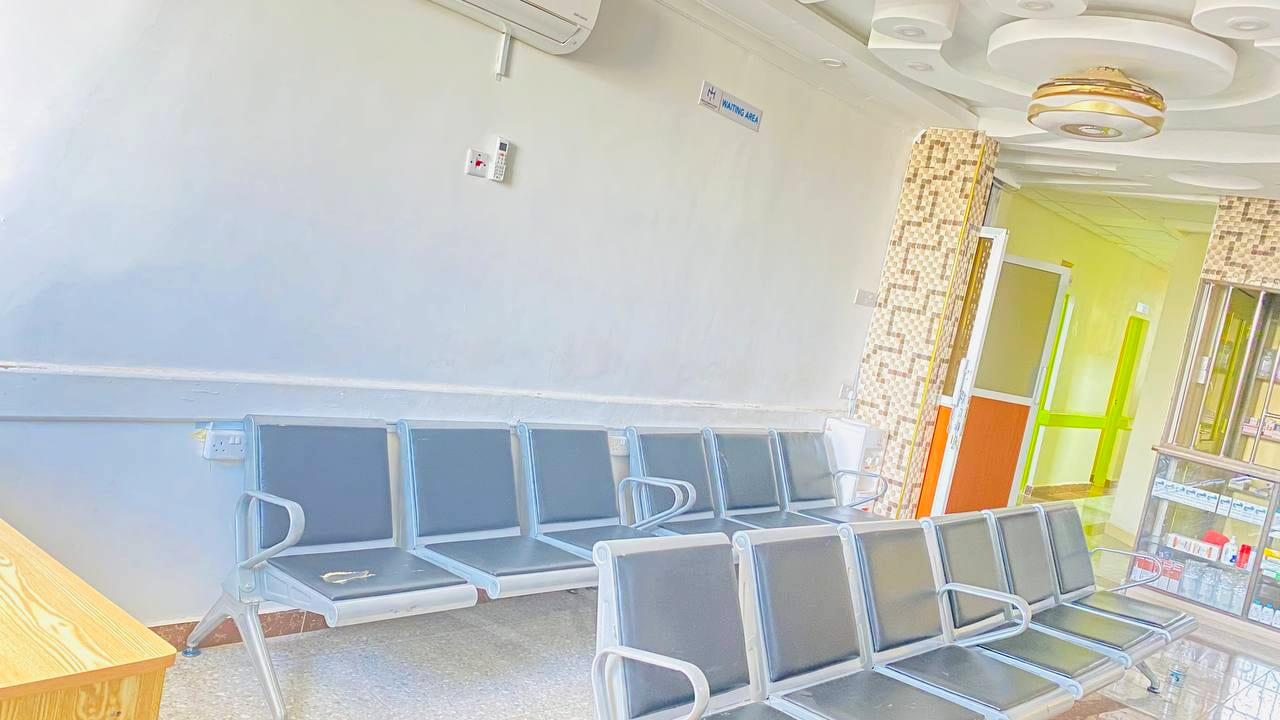 The outpatient waiting area at Namo Hospital, with seating rows, air conditioning and a pharmacy display cabinet.